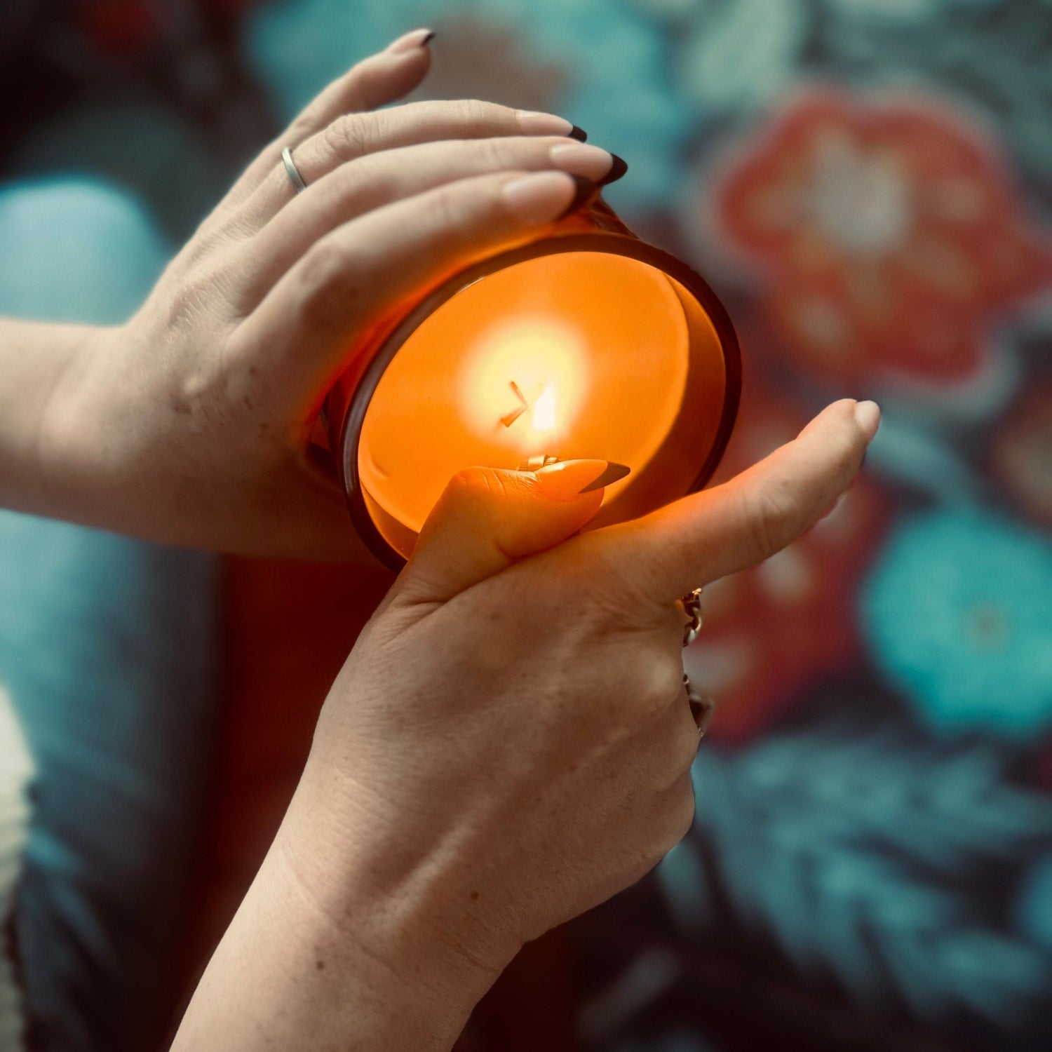 A woman's hands holding our 12 oz Amber Glass Candle, she has the candle tilted to see the wick and is lighting it with a lighter.