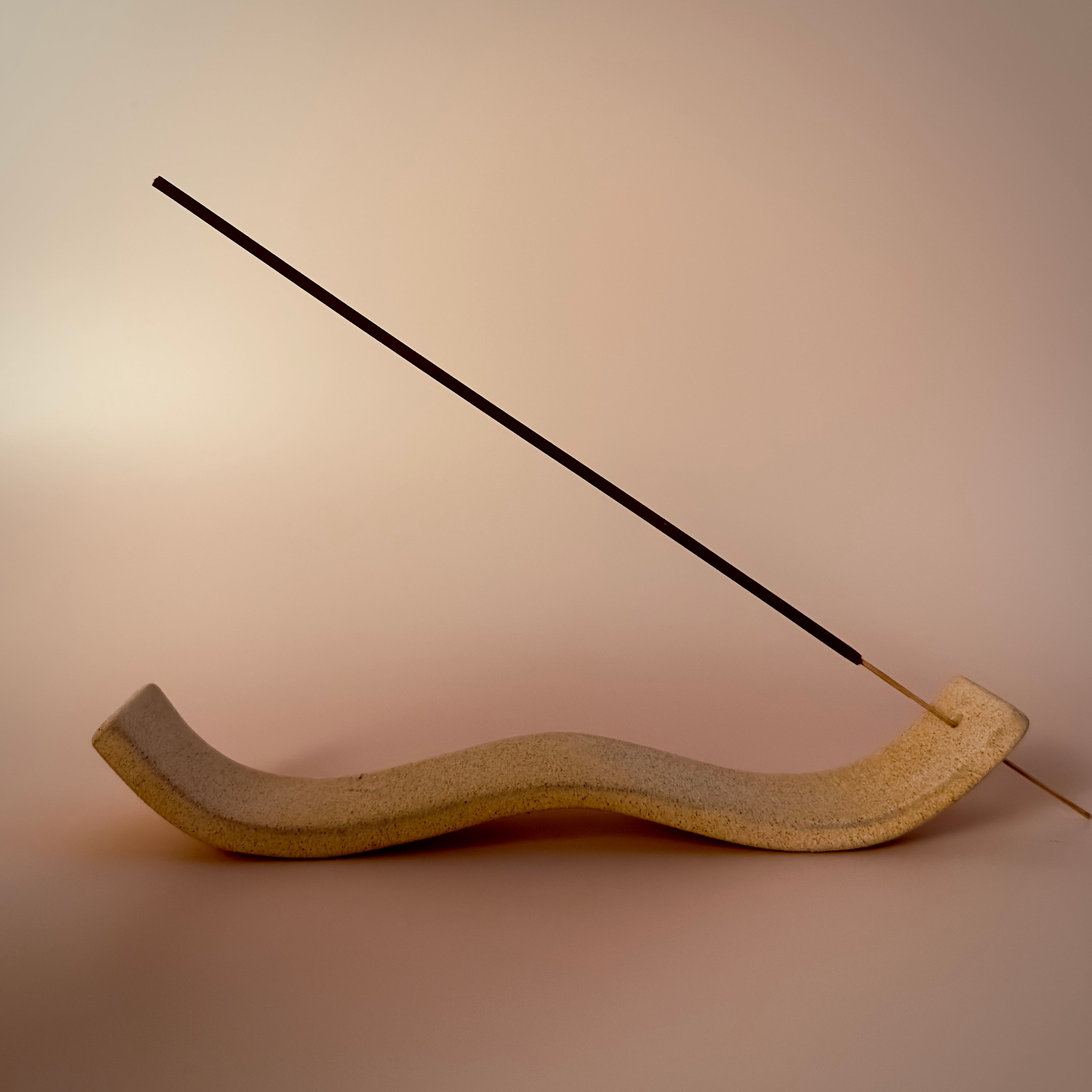 A portrait image of our 11” Floating By incense sticks. A single incense stick is shown in a wavy, stone incense holder.