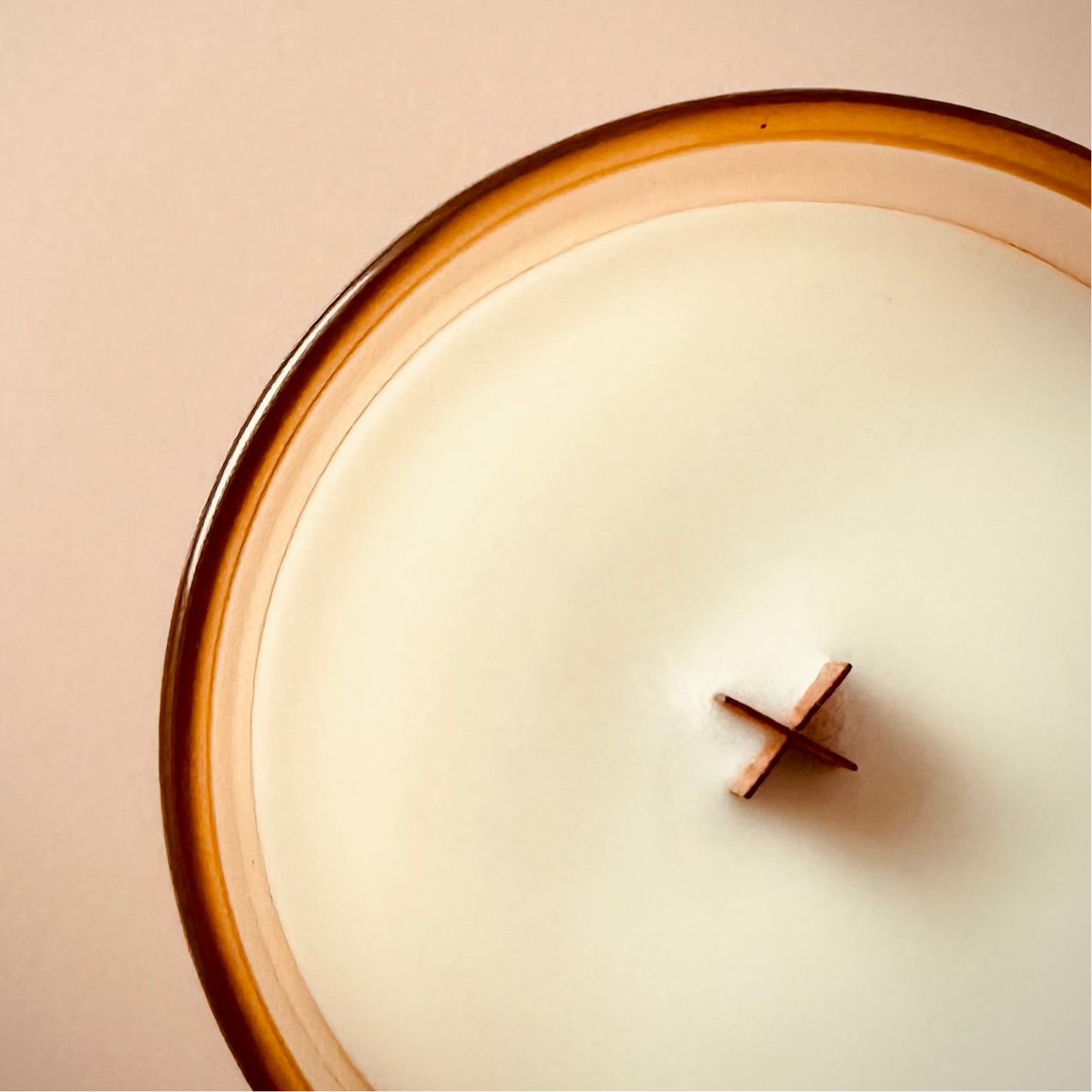 A close up image of our 8oz tinted glass container candle taken from above to highlight our wooden x wick. The lighting is diffused, warm and bright.