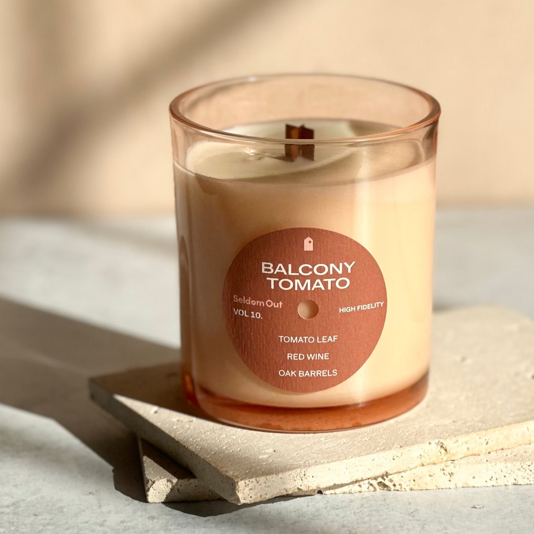 Candle labeled 'Balcony Tomato' on a stone surface with a soft background