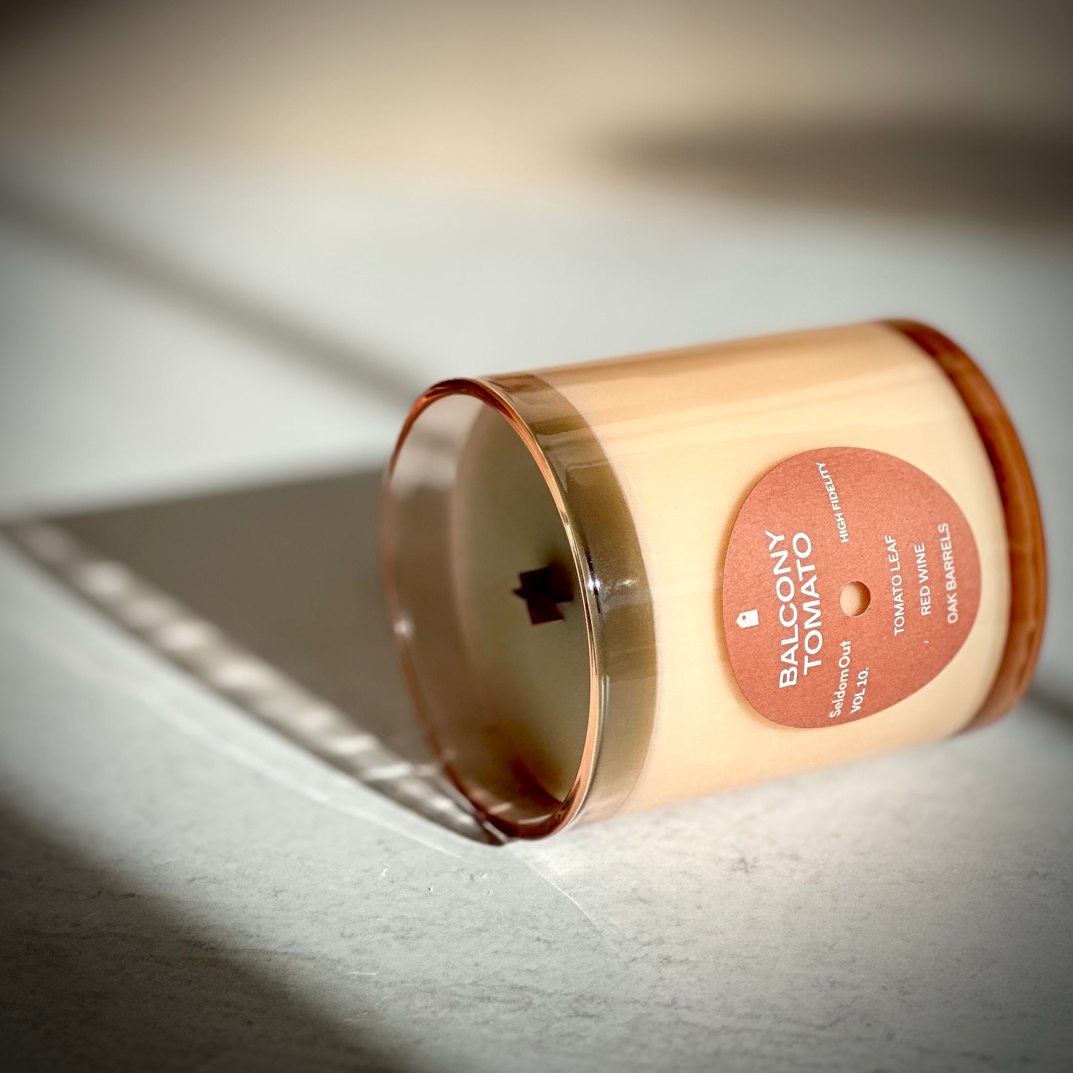 Candle with a 'Balcony Tomato' label on a light surface
