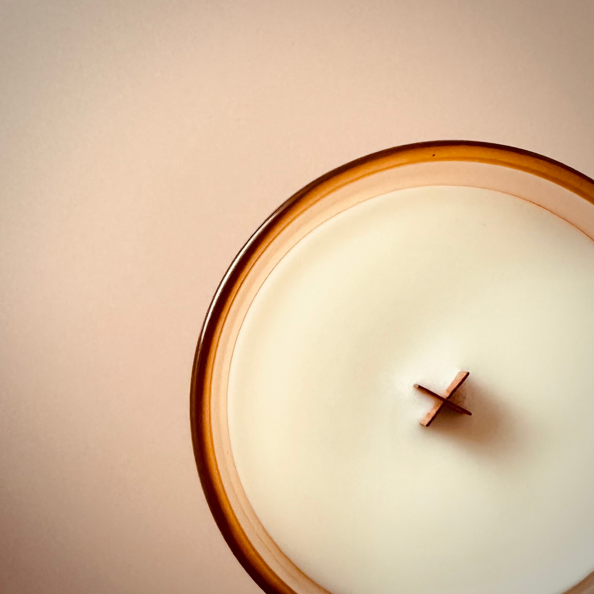 An overhead shot of our Balcony Tomato scented candle, highlighting the wooden X shaped wick. The lighting is diffused and warm.