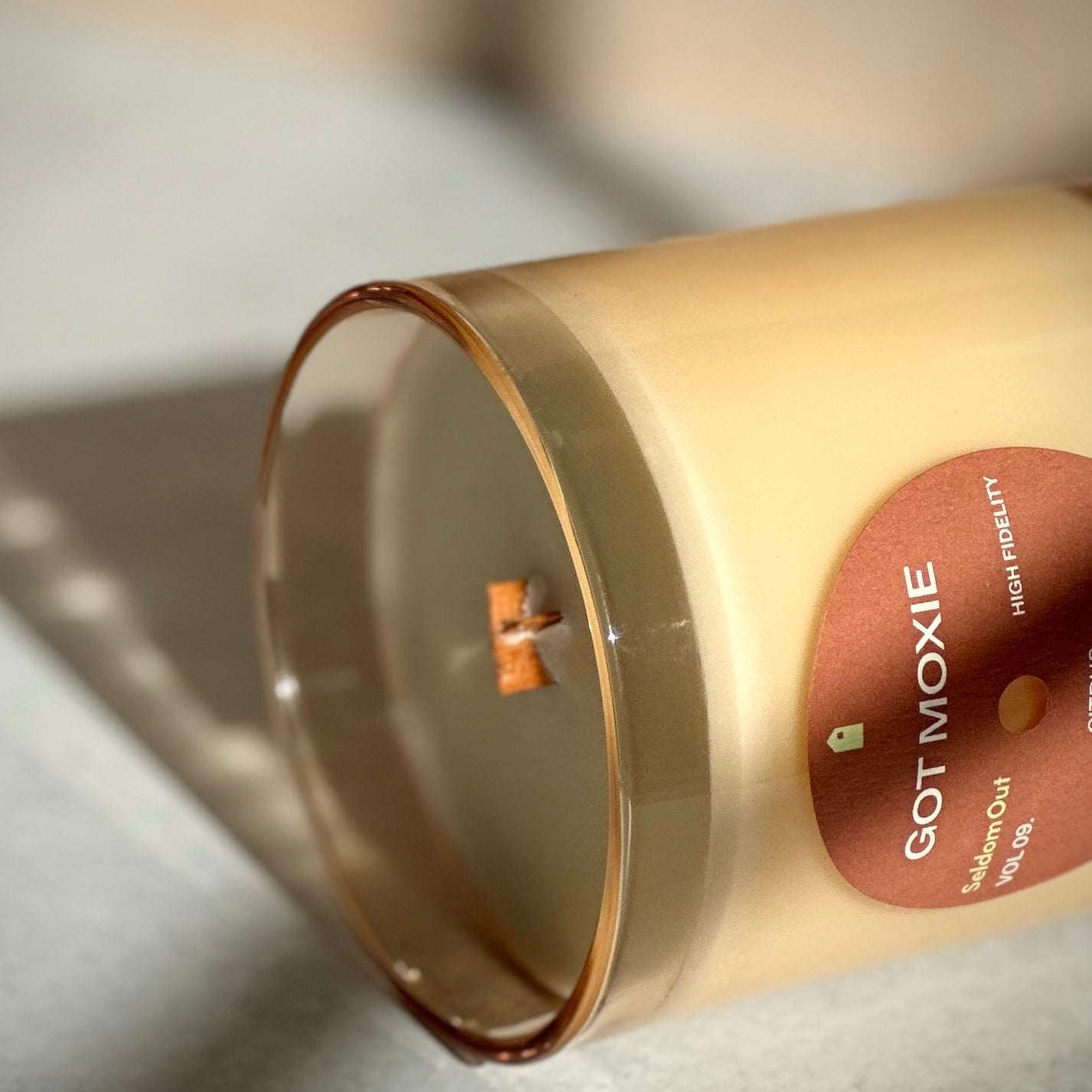 Candle in a glass container with 'GOT MOXIE' branding on a light background