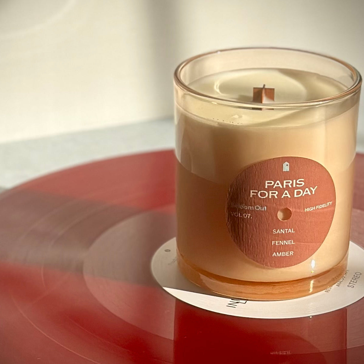 Candle labeled 'Paris for a Day' on a red vinyl record with a blurred background