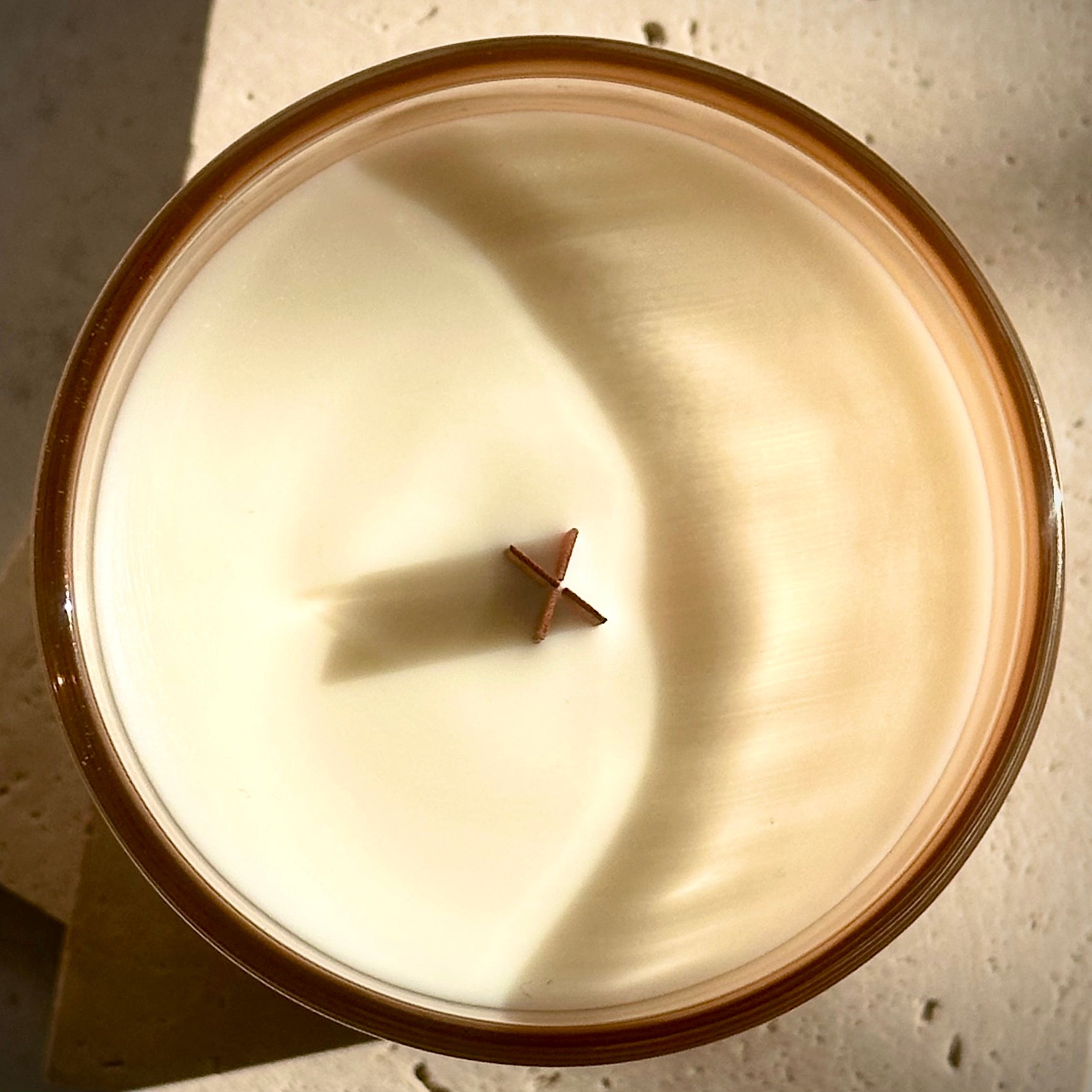 Close-up of a candle with a wooden wick on a textured surface