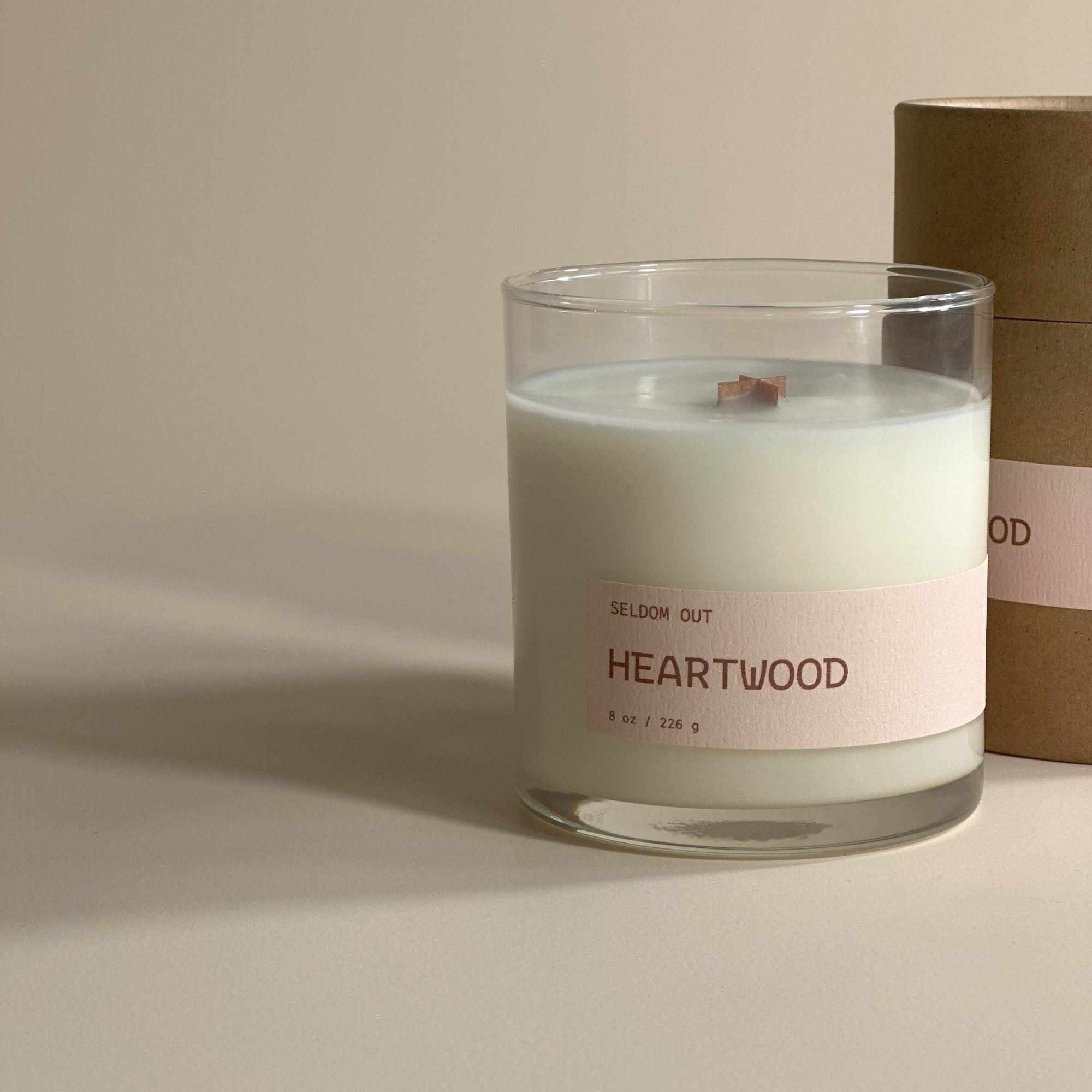 A portrait image of our 8oz Heartwood scented candle. It has a clear glass vessel, with a long thin label.