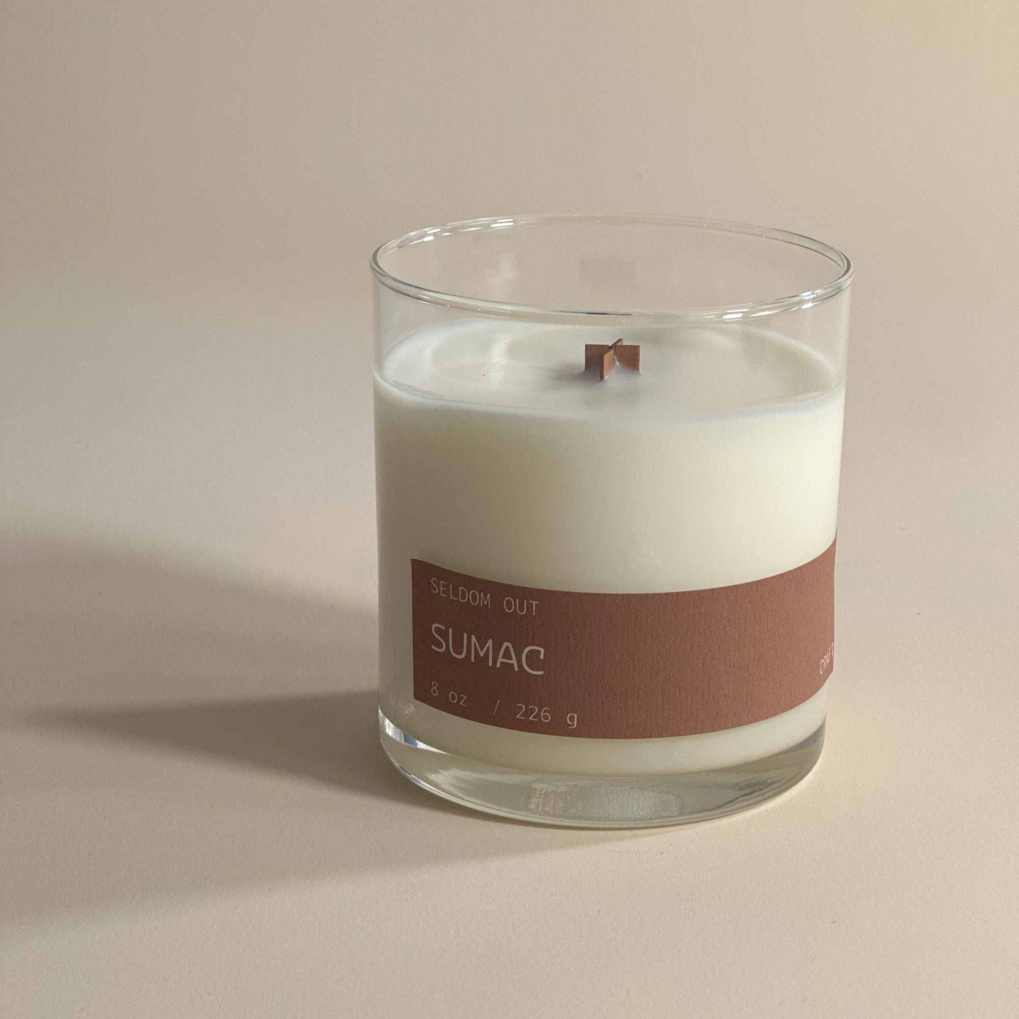 A portrait image of our 8oz Sumac scented candle made in a clear glass jar. It features a simple long thin label that wraps two thirds around the width. 